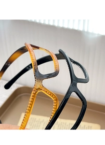 Detail view of eyewear-style hair hoops in amber tortoiseshell and black with non-slip teeth