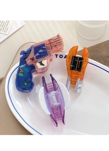 Close-up of creative hair claws including unique revolver and wing designs in a dish