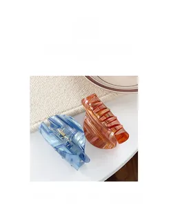 Detail view of acetate claw clips in blue and amber with gold spring mechanisms