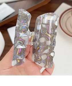 Close-up of a marbled iridescent hair claw clip with colorful textures and metal spring