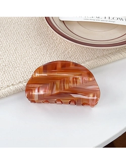 Close-up of amber acetate hair claw with textured caramel streaks and semi-circular design