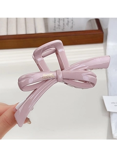 Macro shot of a glossy Morandi pink bow-shaped hair claw clip with golden branding details
