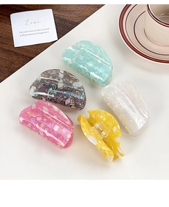 Set of five colorful marble texture hair claws in various shades on white surface