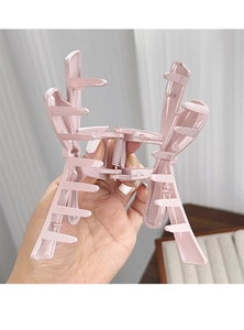Detail of pink large matte hair claw clip held in hand showing secure metal spring