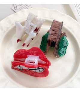 Detail of creative acetate hair claw set including red lips and animal shapes in a ceramic bowl