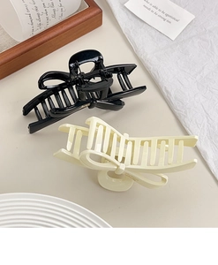 Close-up of black and cream glossy bow hair claws on a minimalist lifestyle background