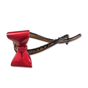 Elegante pinza para el pelo con lazo rojo y acabado de carey sobre fondo blanco