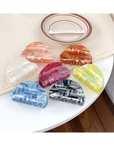Detailed overhead shot of 7 colorful marbled hair claw clips on decorative tray