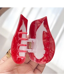 Detail view of red and white flame pattern hair claw clip with golden metal spring