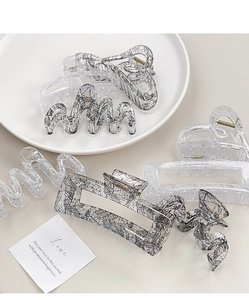 Detailed view of clear acrylic hair claws featuring elegant lace patterns and bow designs