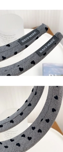 Detail of grey knitted headband with black heart jacquard and hand-made label