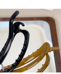 Close-up of black and amber oval hair claws in a tray showing glossy resin texture