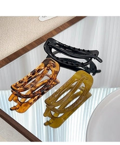 Three large resin hair clips in black, tortoise, and green with a sleek glossy finish