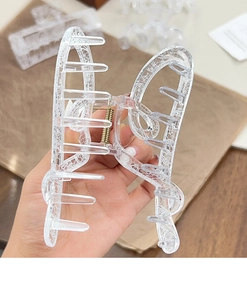Detail of transparent acrylic butterfly hair claw with white lace pattern and gold spring