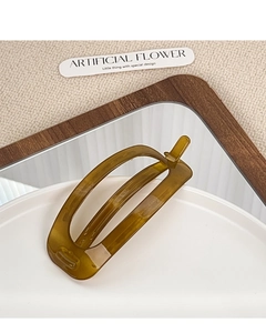 Macro detail of a hollow rectangular amber hair claw clip on a white ceramic plate