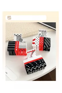Close-up of playing card theme hair claws with red and black suits and rhinestones