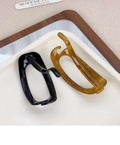 Close-up of elegant square hair clips in black and amber colors on a white tray