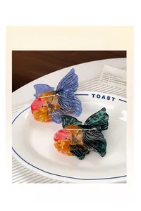 Detail of goldfish shaped acetate hair claws with vibrant blue and green gradients
