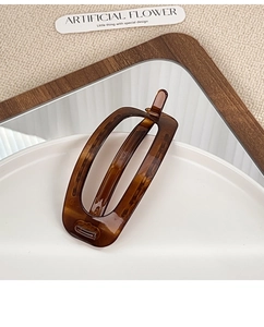 Detail view of oval tortoise shell resin hair clip on white ceramic display plate