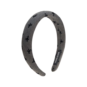 Gray knitted padded headband with black bow patterns and handmade label detail