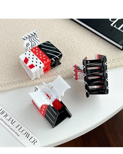 Detail view of acetate shark hair claw with creative playing card pattern in red and black