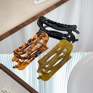Minimalist oval hair claws in black, amber, and green colors for elegant hairstyling