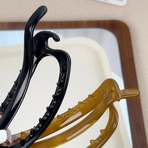 Minimalist oval hair claw clip in amber and black finish with non-slip teeth grip