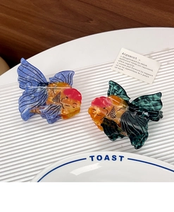 Detail of goldfish hair claws made from marbled acetate with delicate scale patterns