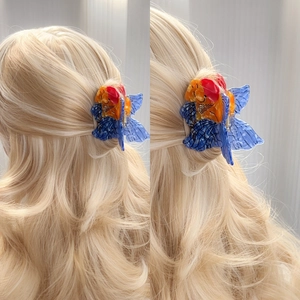 Creative goldfish hair claw clip with orange scales and blue fins on wavy hair