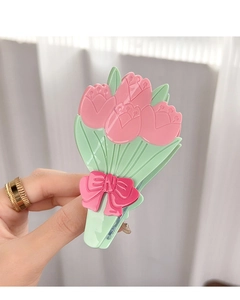 Détail d'une pince à cheveux tulipe avec fleurs roses, feuilles vertes et nœud rose