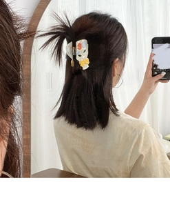 Détail de la pince à cheveux motif tulipe avec nœud jaune sur résine blanc crème