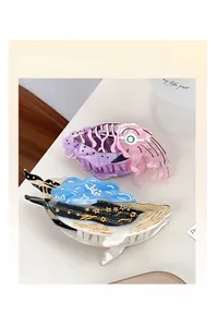 Close-up of ocean-inspired octopus and whale acetate hair claw clips on a desk