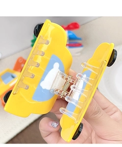 Detail of creative yellow bus shaped hair claw clip with blue accents and sturdy spring