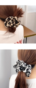 Dettaglio di elastici scrunchie leopardati in seta marrone e grigia su una coda di cavallo