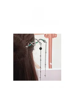 Detailed view of silver snake-shaped hair pin with green enamel and long metal tassels