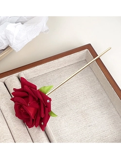 Detailed view of red fabric rose hair pin with rhinestones and gold-tone metal stem