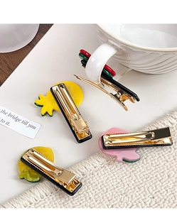Detailed view of four colorful acetate fruit hair clips including pineapple and peach