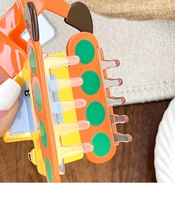Macro shot of creative orange excavator claw clip with glossy finish and green accents