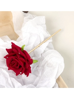 Detail of red rose hair pin with rhinestone accents and golden metal stick on paper