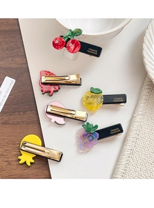 Close-up of acetic fruit-shaped hair clips with fine rhinestones and golden metal clips