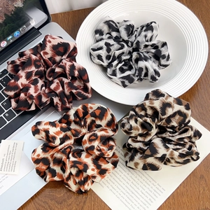 Set di quattro elastici per capelli con stampa leopardata su scrivania in legno