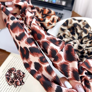 Elastico per capelli in raso setoso con stampa leopardata per donna su sfondo scrivania