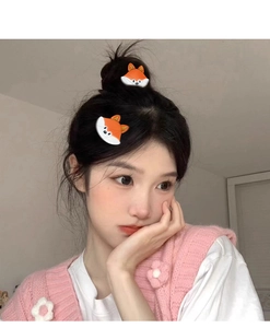 Detail showing two cartoon fox hair clips worn on the side of a person's hairstyle