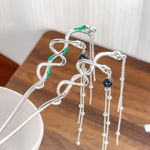 Detailed view of silver snake hairpins with green enamel and long tassel chains