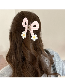Roze en wit gestreepte haarspeld met strik en witte madeliefjes op een half-up kapsel