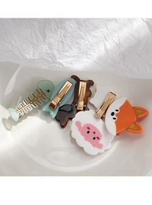Macro detail of various animal shaped acetate hair clips in a white ceramic dish