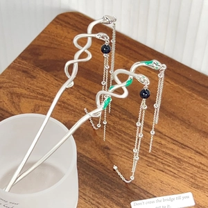 Silver snake-shaped hair stick with green accents and long metallic fringe tassels