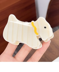 Détail d'une pince à cheveux chien Scottie à rayures crème et marron tenue à la main