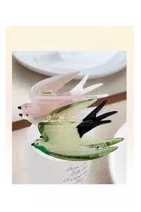 Detail of bird-shaped hair claw clips in pink and green gradient acetate finish