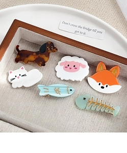 Assorted acetate cartoon animal hair clips including dachshund and fox in wooden tray